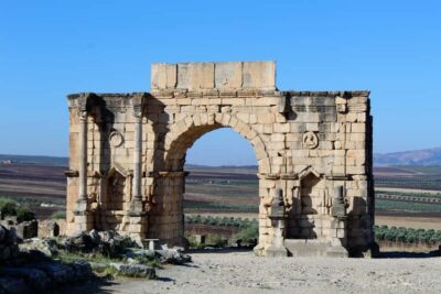 From Fez: Volubilis Moulay Idriss and Meknes Day Trip - Volubilis Roman ruins: the Arch of Caracalla and the big-picture layout